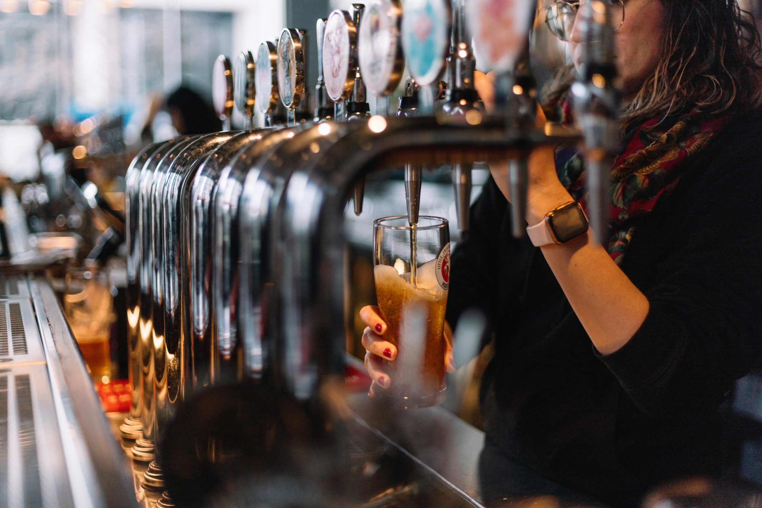 a bartender pulls a tap and pours a blonde ale