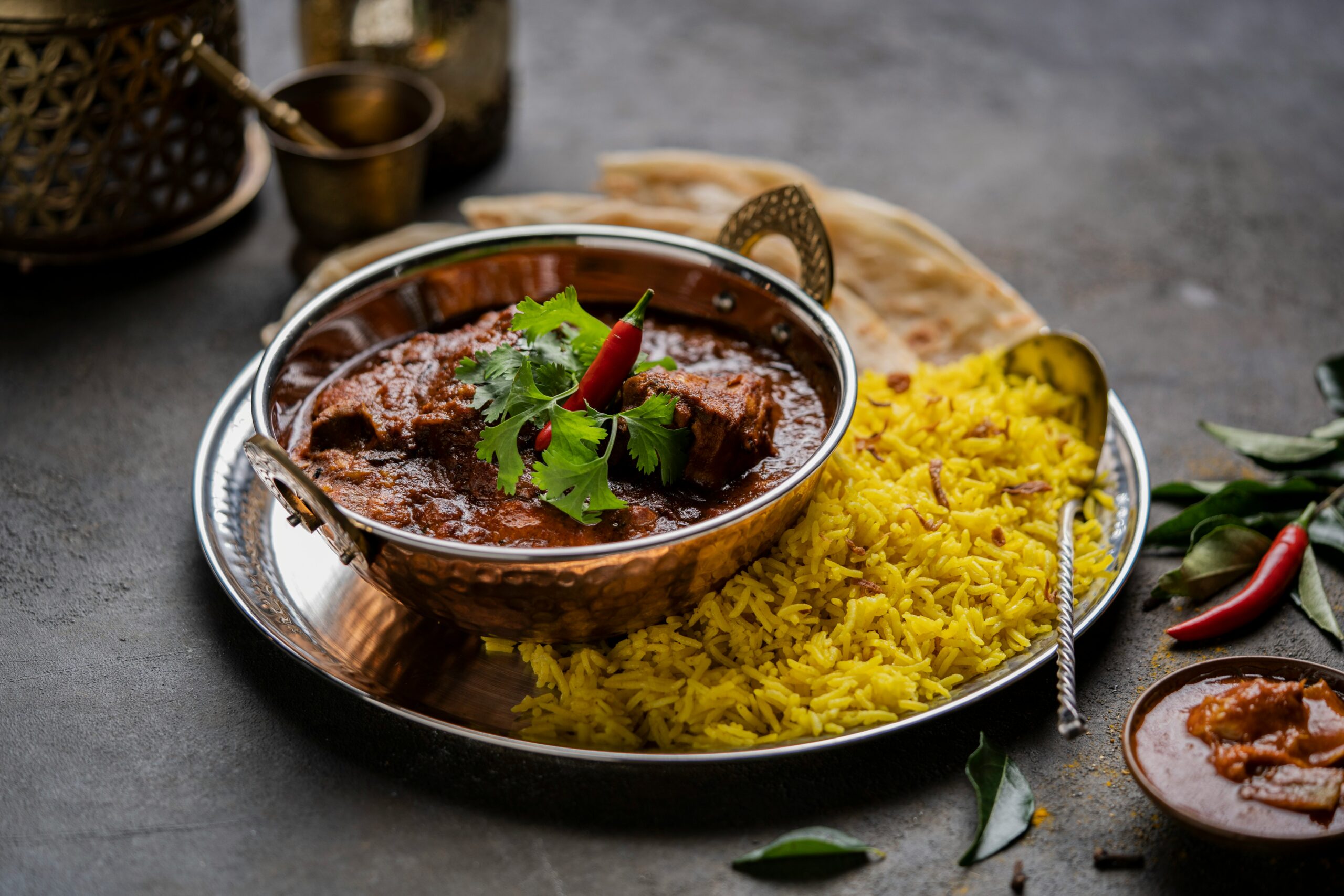 A traditional plating of Lamb Rogan Josh served with rice and garnished with red peppers